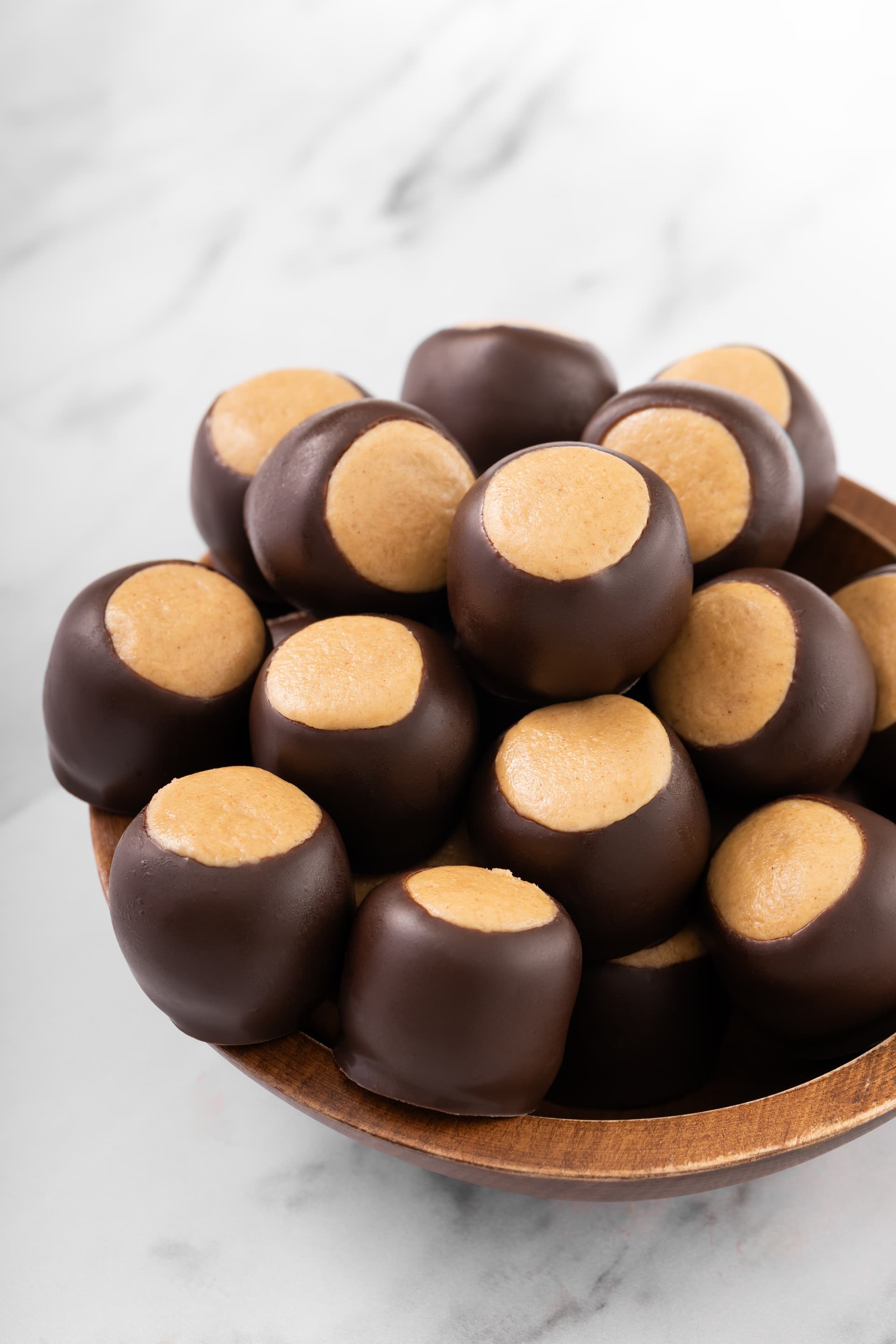 Three Ohio buckeye nuts showing the distinctive shiny dark-brown shell with a light tan patch